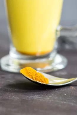 a spoon filled with turmeric powder