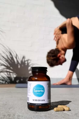 sports formula multivitamin jar kept in natural lighting with a person exercising in the background