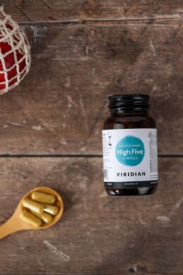 high-five multivitamin mineral-formula jar 30 caps kept on wooden surface with a spoonful of capsules